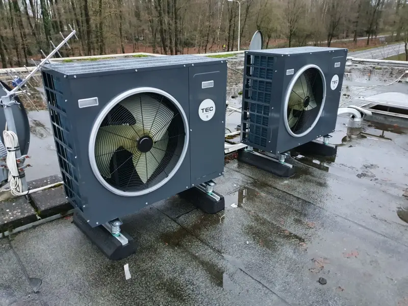 Buitenunit van een warmtepomp op een plat dak, geplaatst door Groenere Woning